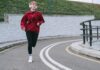 a woman in red pullover jogging while listening to music